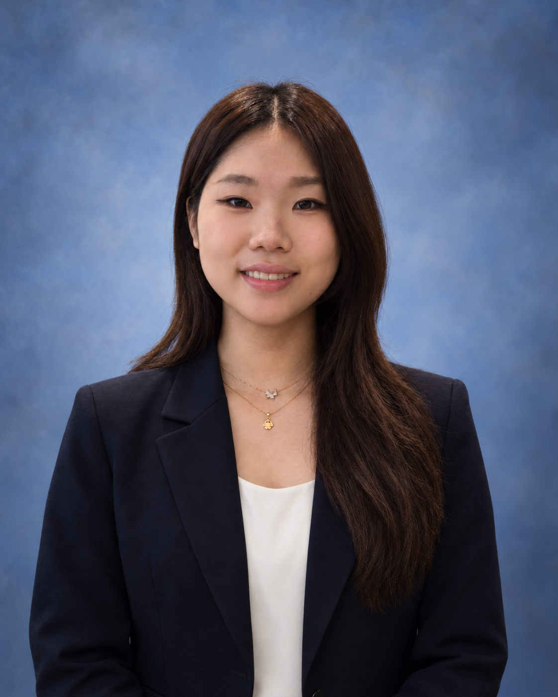 Jeemin Park smiling in a navy blazer against a blue-gray studio backdrop